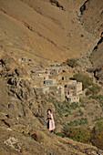 Girl in the mountains, houses of a village in the back, Marrekech area,  High Atlas, Morocco
