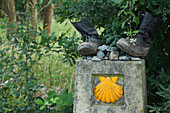 Alte Stiefel auf Wegstein mit Jakobsmuschel, Provinz La Coruna, Galicien, Nordspanien, Spanien, Europa