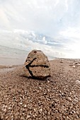 Stein mit Wegweiser am Strand