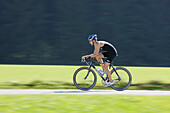 Man cycling with a triathlon bike on road near Munsing, Upper Bavaria, Germany