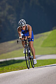 Frau mit einem Triathlon-Fahrrad auf einer Landstraße bei Münsing, Oberbayern, Deutschland