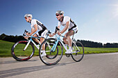 Zwei Radrennfahrer auf einer Landstraße bei Münsing, Oberbayern, Deutschland