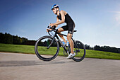 Man cycling with a triathlon bike on road near Munsing, Upper Bavaria, Germany