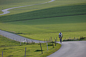 Man mountain biking on road near Munsing, Upper bavaria, Germany