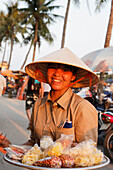 Woman offering sweets in harbor, Hoi An, Annam, Vietnam
