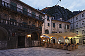 Restaurant at a square in the evening, in the background fortress on a hill, Kotor, Montenegro, Europe