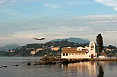 Airplane flies above the 17th century church of the Vlacherna Corfu, Greece