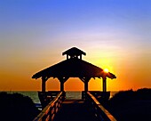 Silhouette of a gazebo among the sand dunes with the ocean in the background