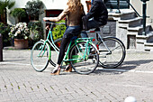 Young couple on bicycles standing talking on the streets, Amsterdam, Netherlands