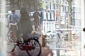 Verkehrsszene mit Fahrrad spiegelt sich in einer Scheibe in der Innenstadt von Amsterdam, Niederlande