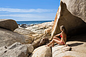 Frau sonnt sich am Felsstrand, Bucht von Algajola, Korsika, Frankreich