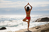Woman exercising yoga at beach, bay of Algajola, Corsica, France
