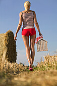 Young woman with picnic basket walking through stubblefield