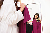 Junge Frau probiert Kleider vor einem Spiegel, München, Bayern, Deutschland