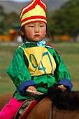 Four-year-old girl riding a horse, participant in the horsemanship competition of the Naadam Festival, Mongolia