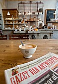 Detail of coffee and local newspaper in traditional bakers shop and cafe in central Antwerp in Belgium