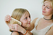 Teenager combing girl's hair