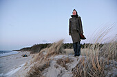 Woman standing in dunes, Baltic sea spa Ahrenshoop, Mecklenburg-Western Pomerania, Germany