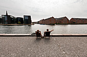 Couple relaxing on the banks of the Havnebadet canal, Copenhagen, Denmark