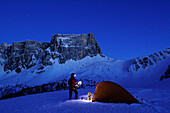 Woman with snow shoe standing in front of tent on snow face in front of Croda da Lago and Monte Formin, Passo Giau, Cortina d' Ampezzo, UNESCO World Heritage Site Dolomites, Dolomites, Venetia, Italy, Europe