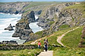 Coast walkers on the South West Coast Path north of Newquay, Cornwall Backdrop of the sea stacks and cliffs of Bedruthan Steps
