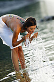 Frau mittleren Alters erfrischt sich im seichten Wasser