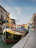 Boat in a Canal Lined With Colorful Homes, Venice, Italy