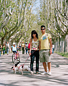 Couple walking their dogs, sycamore tree lined path through Parque Primo de Rivera, Saragossa, Aragon, Spain