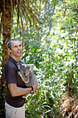 Tourist hält Koala, Bungalow Bay Koala Village, Horseshoe Bay, Nordküste Magnet Island, Great Barrier Reef Marine Park, UNESCO Weltkulturerbe, Queensland, Australien, Weltnaturerbe