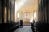 Mönch betet vor Altar in romanischer Kirche San Antimo, San Antimo, Toskana, Italien