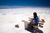 Bolivia, Southern Altiplano, Salar de Uyuni Tourist resting on a seat constructed of salt, located on the Salar de Uyuni salt flat