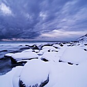 Snow covered rocks at Unstad beach, Vestvågøy, Lofoten islands, Norway