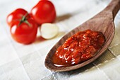 Wooden spoon filled with tomato sauce