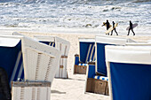 Surfers at beach, roofed wicker beach chairs in foreground, Westerland, Sylt, Schleswig-Holstein, Germany