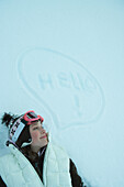 'Teenage girl lying on snow next to thought bubble and the word ''hello'''