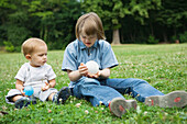 Girl with Down's Syndrome sitting with baby brother on the ground, both playing with balls