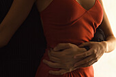 Couple embracing, man's arm around woman's waist, close-up, cropped