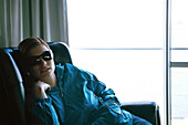 Woman slouching in armchair, wearing sunglasses