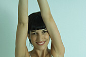 Young woman smiling at camera, arms raised