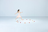 Young woman running, leaping into circle of flowers