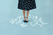 Woman's feet surrounded by artificial white leaves scattered on floor