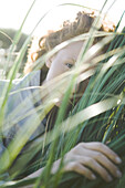 Woman hiding in tall grass, close-up