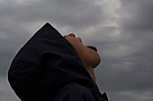 Boy with head back catching raindrops on tongue