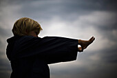 Boy with arms outstretched looking through finger frame