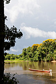 People on boat traveling down river along rainforest