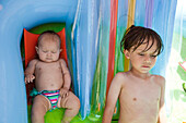 Young boy and baby sibling in pool