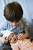 Young boy touching baby sibling's cheek