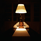 Man at end of table with head on table