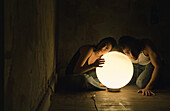 Woman and man putting ears to glowing orb