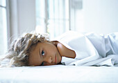 Girl lying in bed, looking into camera